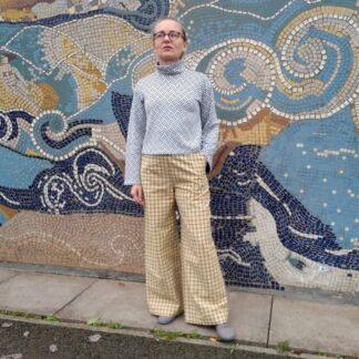 woamn dressed in grey turtleneck and yellow check trousers