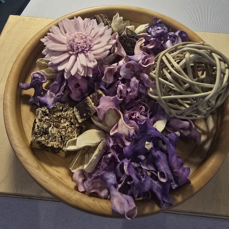 Hand-turned alder wooden potpourri bowl filled with purple dried petals and botanicals, showing the smooth honey-toned grain of the wood.