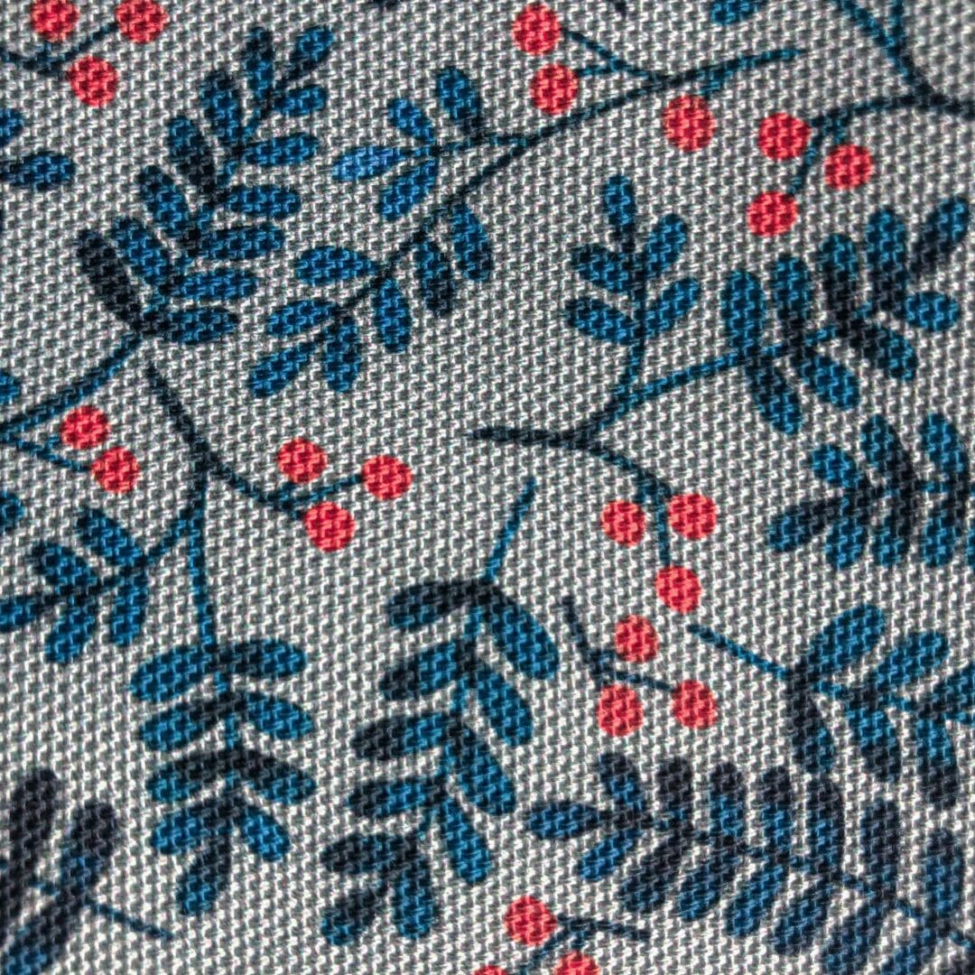 Close-up of the Berries Tea Towel fabric showing delicate blue leaves and red berries on textured cotton.