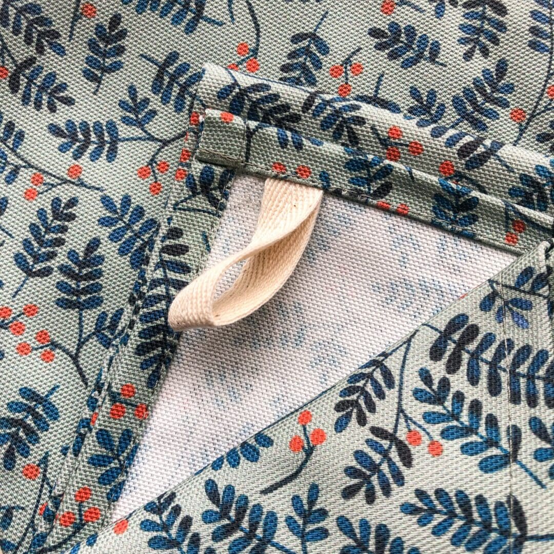 Close-up of the hanging loop sewn into the corner of the Berries Tea Towel, showing the botanical berries print and neat stitching.