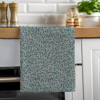 A soft green cotton tea towel featuring a hand-illustrated botanical berries pattern hanging neatly on a wooden oven rail in a bright kitchen.