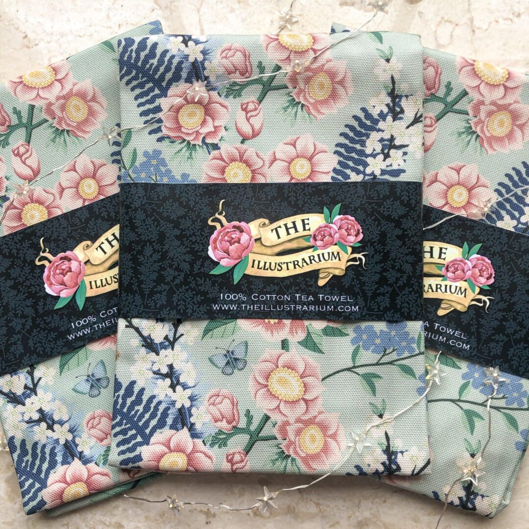 Folded chinoiserie floral cotton tea towels with The Illustrarium branded belly band, printed in the UK.