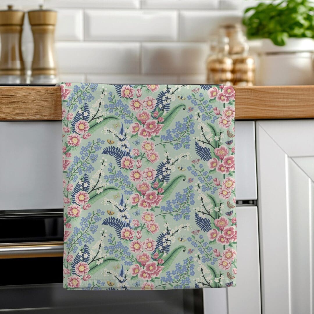 Hand-illustrated Chinoiserie floral tea towel hanging on an oven rail, designed by The Illustrarium, printed in the UK on 100% cotton.