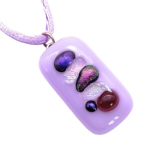 A rectangular lilac dichroic glass pendant with iridescent multicolored pieces is suspended from a matching lilac cord. The design is vibrant and elegant.