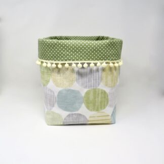 Fabric storage cube in a circles fabric with a pom pom fringe.