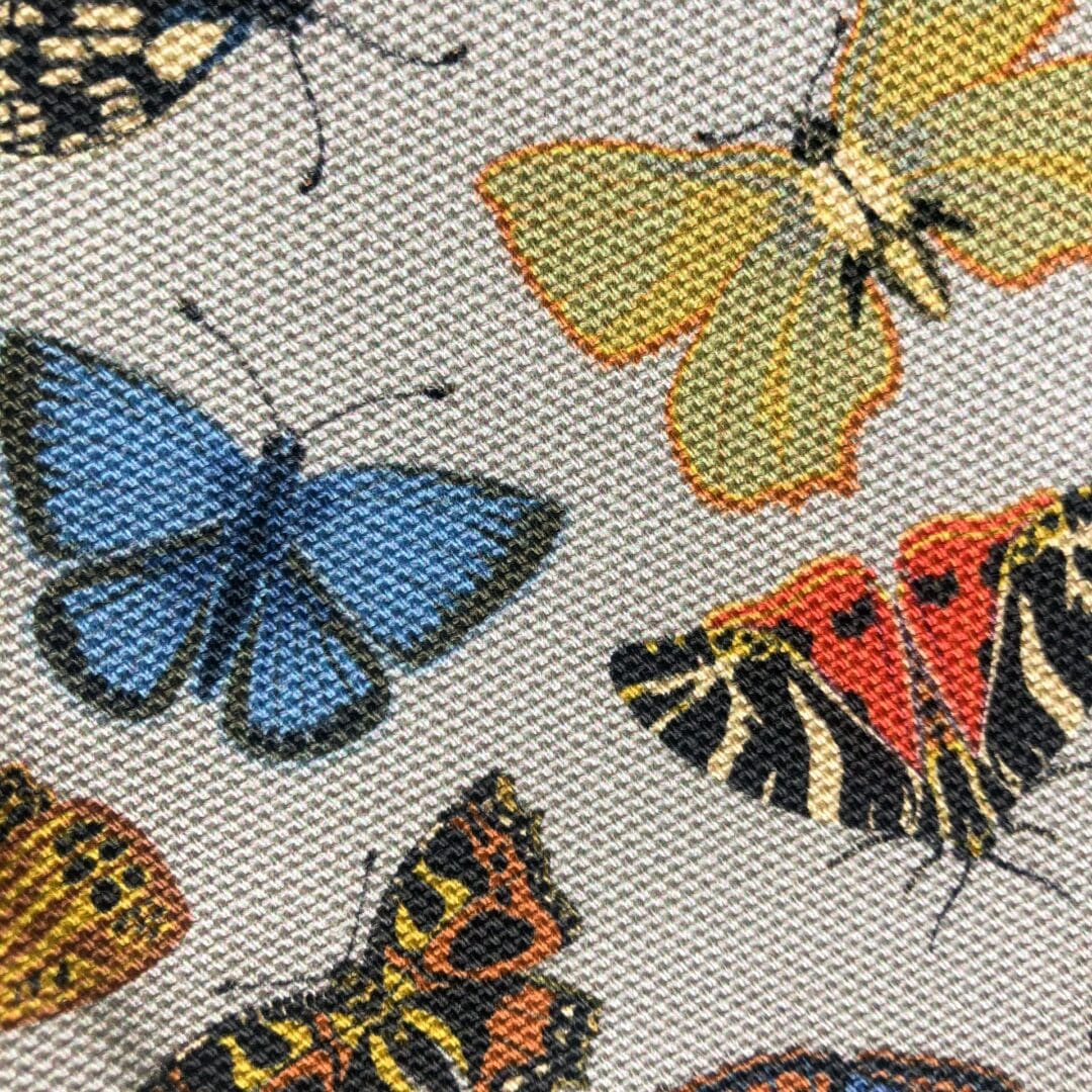 Macro close-up of the Folk Butterflies Tea Towel fabric showing blue, yellow, and red butterflies printed on natural cotton.