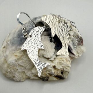Hammered 925 sterling silver dolphin drop earrings on an oyster shell