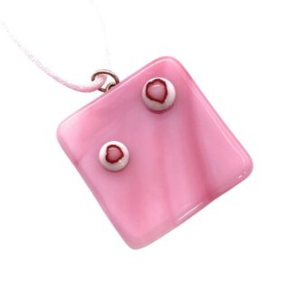 A pink square handmade glass pendant with a glossy finish features two circular shapes with pink heart designs. It hangs from a delicate, light pink cord.