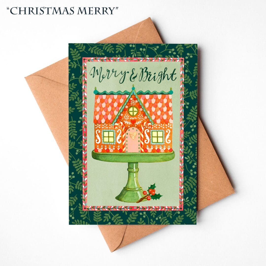 A hand-illustrated Christmas card featuring a festive gingerbread house with the words “Merry & Bright,” displayed on a natural brown Kraft envelope.