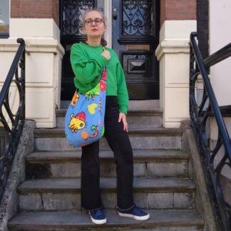 woman in green top holding large blue tote bag