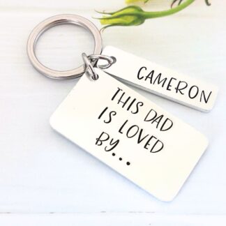rectangular aluminium keyring hand-stamped with the words 'this dad is loved by' with personalised name tags