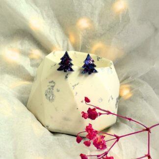 Pair of sparkly purple tree studs on a festive lit background.