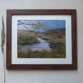 The picture depicts hills and moors with a stream in the foreground and the branches of a tree with autumn leaves.