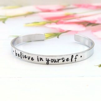 A hand-stamped aluminium cuff bracelet with the wording believe in yourself on the front