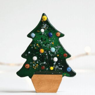 Small freestanding green fused glass Christmas tree with textured, colourful detail, resting in a simple square wooden base. This handmade, unique glass decoration is 13.5cm tall and is perfect for a mantel or shelf display. It is sold as a luxury holiday gift or home accessory. It is sent in two pieces, wrapped in tissue paper and purple ribbon, ready to be given as a present.