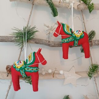 Red felt Dala inspired horse with brightly green white yellow and brown stitched mane and saddle by lyndawilcansew hanging on a Christmas tree branch