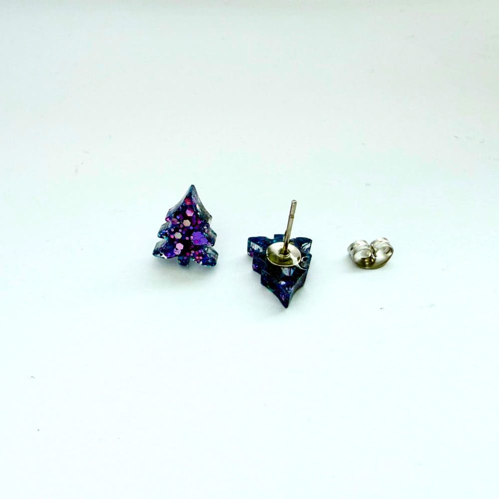 Close-up of purple glitter Christmas tree stud earrings shopwing the stud and butterfly back on a white background