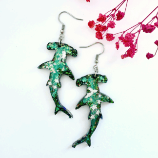 Beautiful shimmering glitter hammerhead sharks with marine life impressions and "salt spray" glitter embellishment on a white background with pink flower decoration.