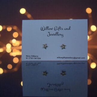 Silver star stud earrings in front of fairy lights
