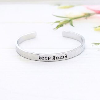 A 6mm wide adjustable aluminium cuff bracelet hand-stamped with the motivational words keep going
