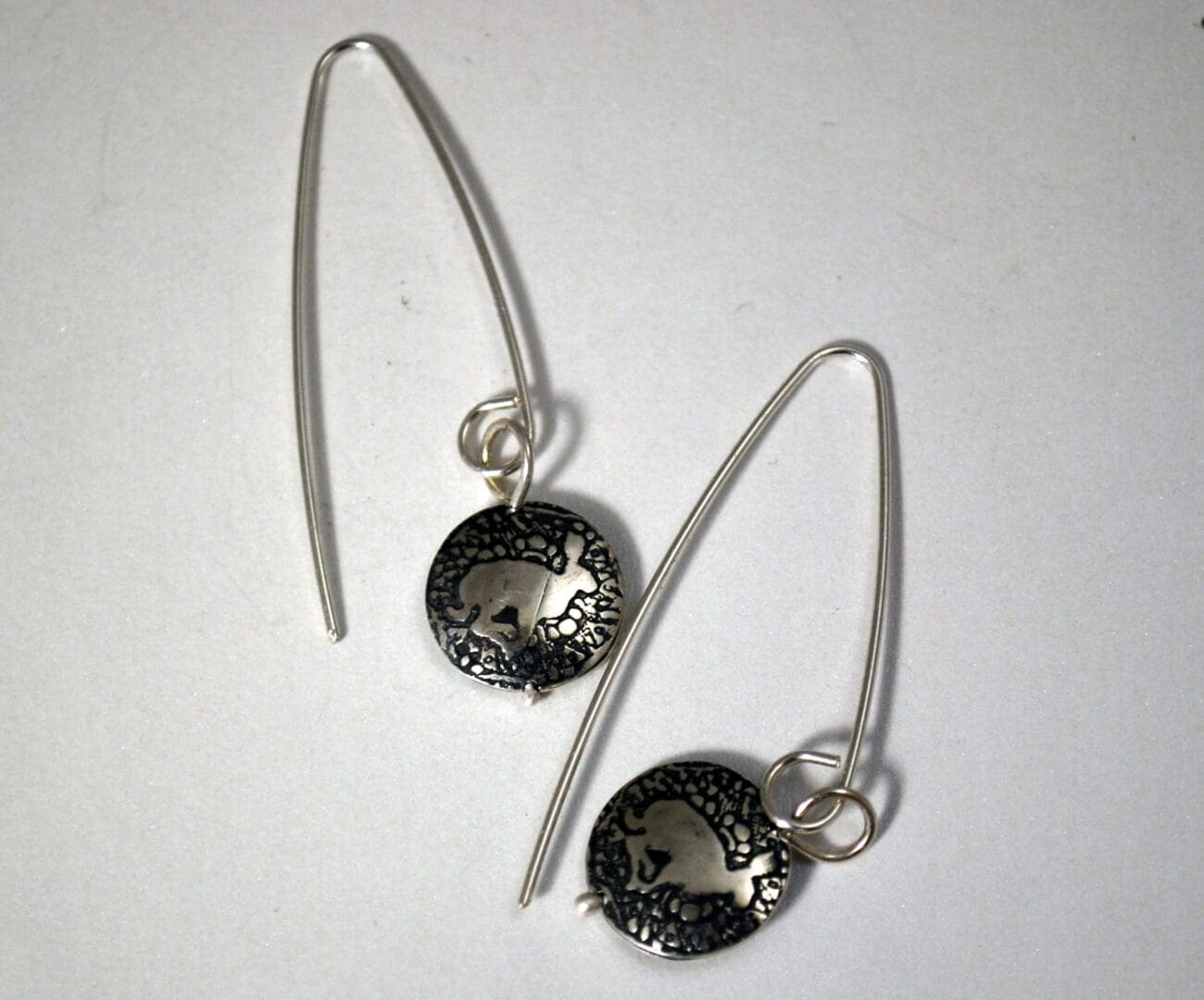 Silver dangle earrings featuring etched running hare motifs on a mandala-patterned disc, perfect for a bohemian or nature-inspired look