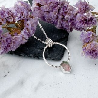Watermelon tourmaline gemstone with green and pink hues set in a silver circle necklace