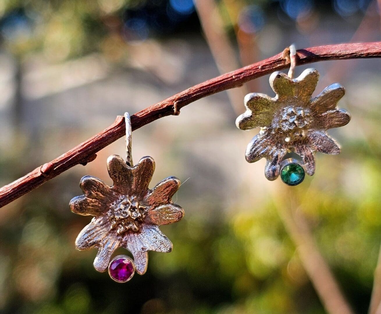 9ct gold, laboratory ruby & sterling silver, tsavorite garnet hand carved flower earrings, shot on branch outdoors, Isobel Kelly Jewellery
