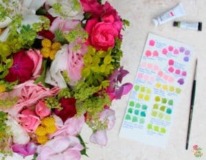 Bouquet of colourful flowers next to an artist’s colour palette card with paint swatches.