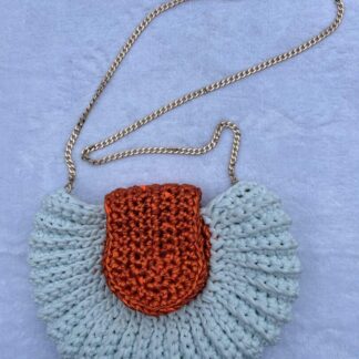 A small, silver-grey handbag resembling an Oreo cookie shape, featuring a textured surface and a shiny gold shoulder chain.