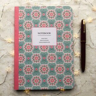 A hand-painted A5 notebook with a pink and green daisy floral pattern, styled with a red fountain pen and soft fairy lights on a marble background.