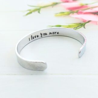 wide hammered texture aluminium cuff bracelet with the message 'I love you more' hand-stamped inside