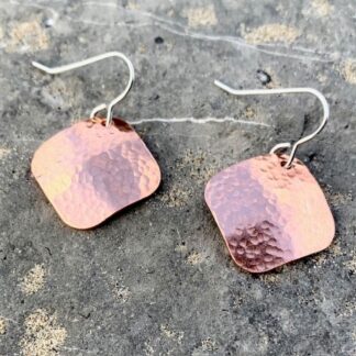 Square hammered copper dangle earrings on a dark natural grey stone