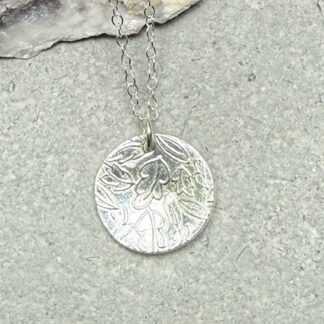 Textured Pure Fine Silver Leaf Disc Necklace displayed on a natural grey stone