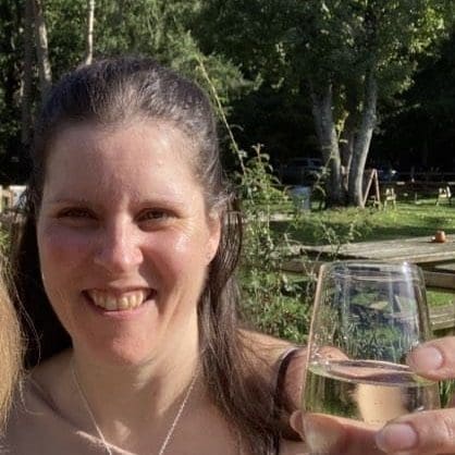 Woman smiling and holding a wine glass up to the camera