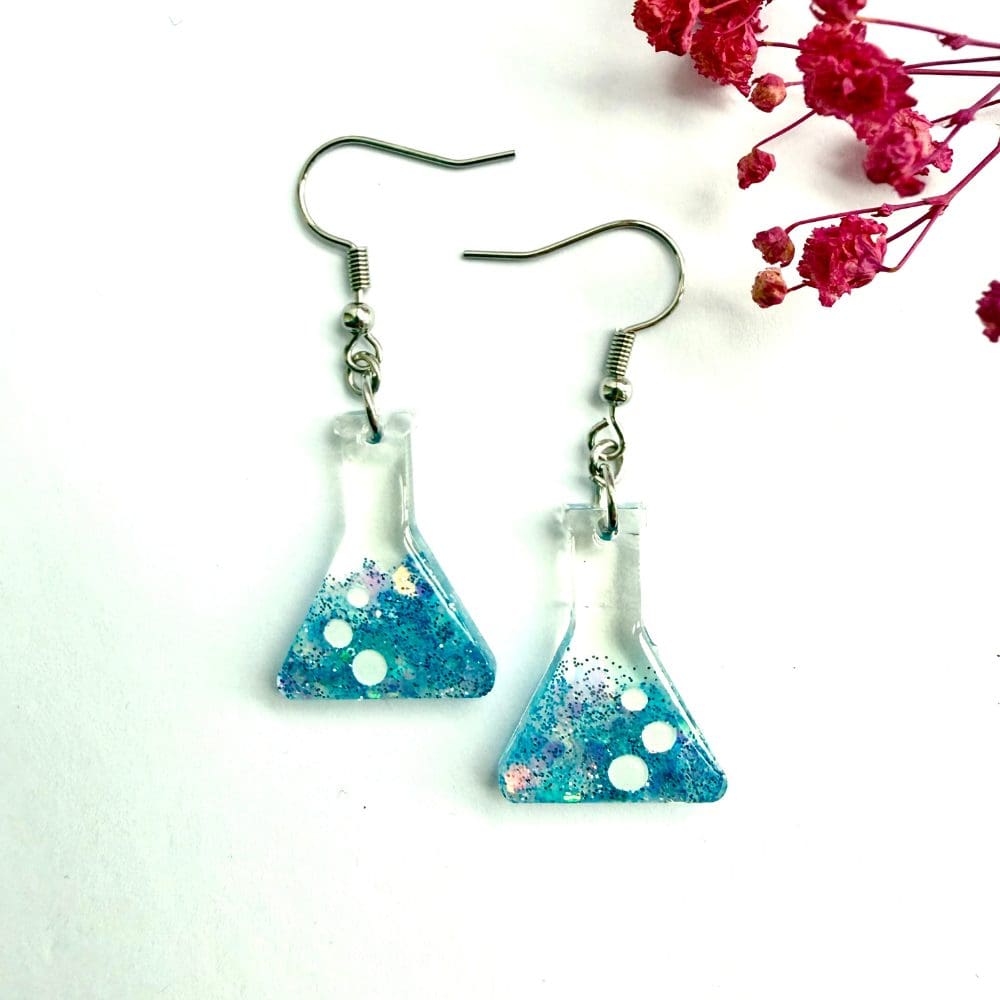 Close-up of resin flask earrings with ocean blue glitter and white shimmer