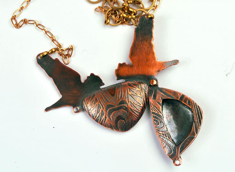 copper rook locket featuring two flying crows in a symmetrical design. Photographed on a white background showing the piece opened from the back.