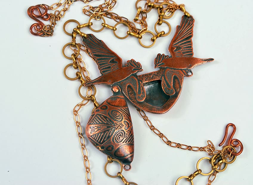 copper rook locket featuring two flying crows in a symmetrical design. Photographed on a white background showing the piece opened from the front.