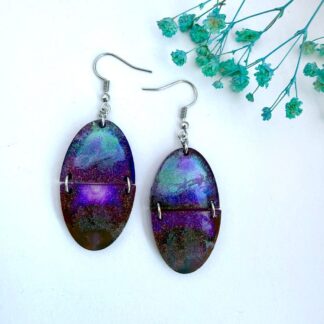 Handmade resin earrings with Santa and his sleigh etched over a purple and teal northern lights background, split oval design with glitter shimmer