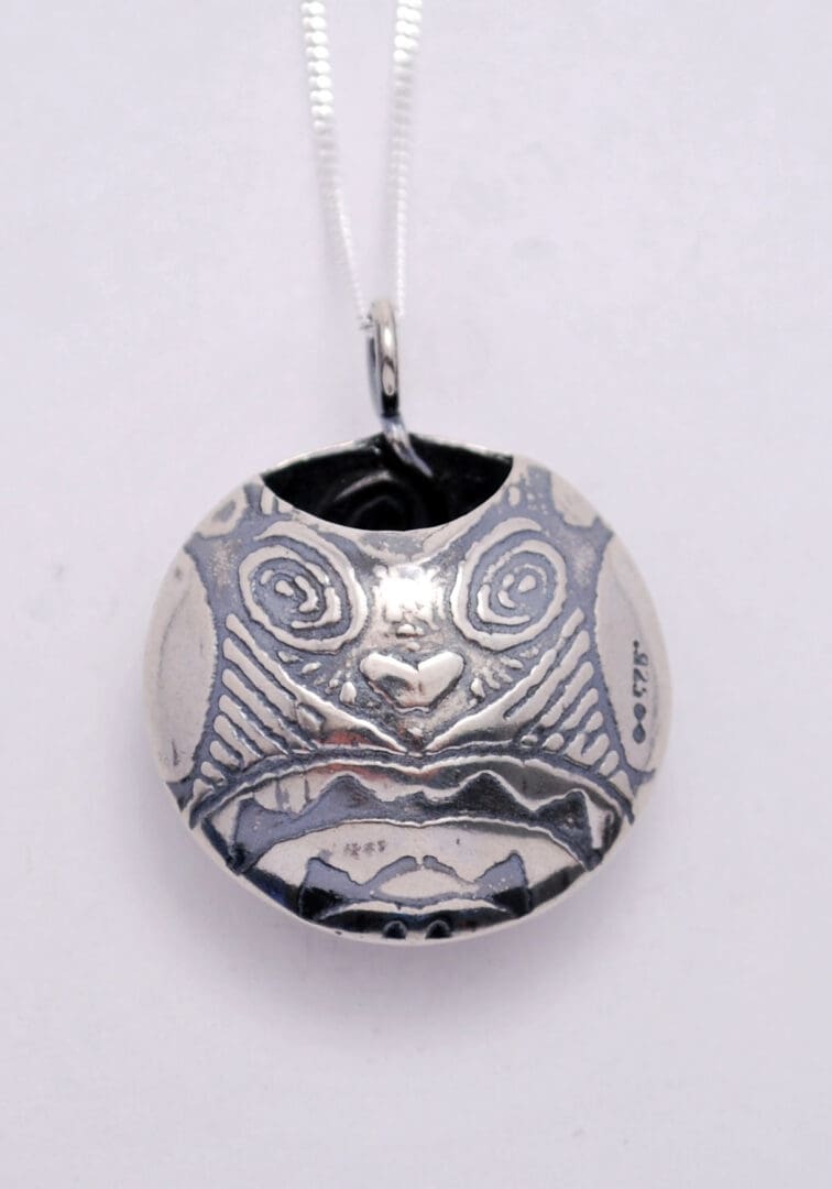 sterling silver patterned scent locket on white background, shown from rear to illustrate opening.