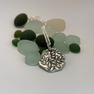 A fine silver leaf pendant in a rounded hexagonal design with light patina finish.