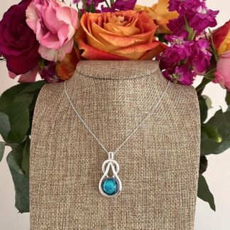 Silver celtic knot style pendant with a sparkly turquoise dichroic glass centre