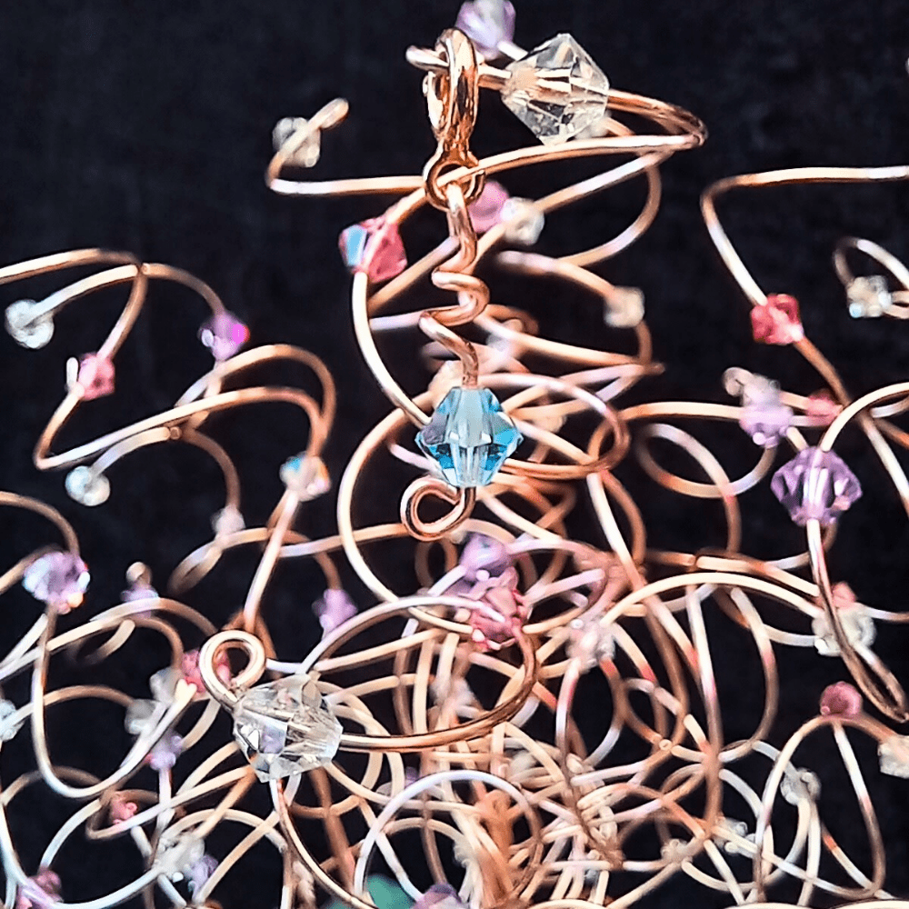 An aquamarine crystal that has been attached to a wire tree branch with a bolt clasp so it hangs from the end of the branch.