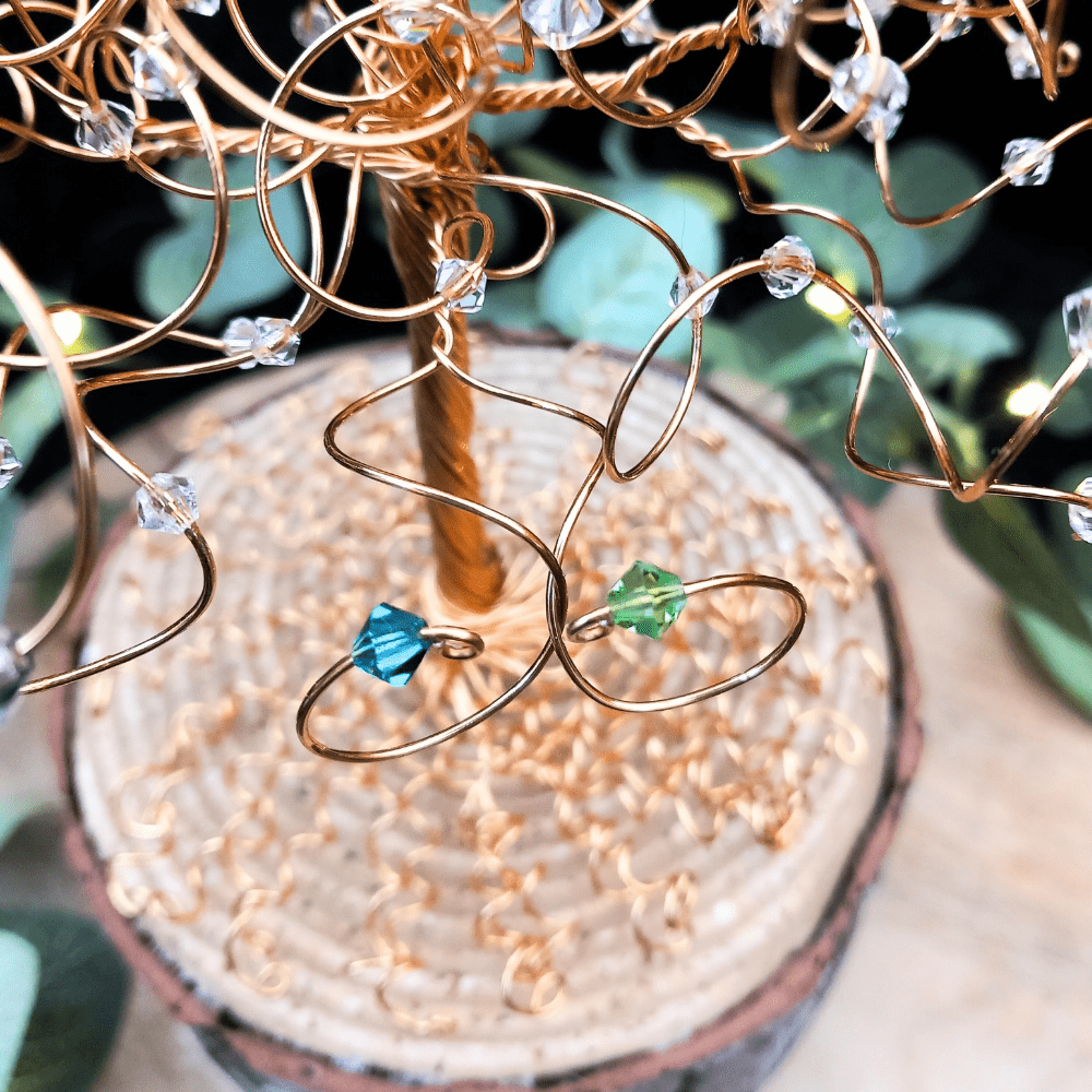 Gold wire two entwined branch detail on a wedding cake topper tree with birthstones on each branch in blue zircon and peridot.