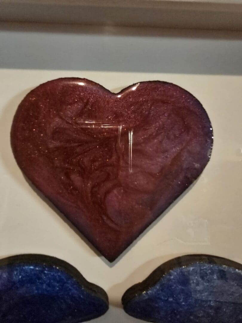 Framed resin wall art showing two dolphins beneath a red heart in a white box frame.