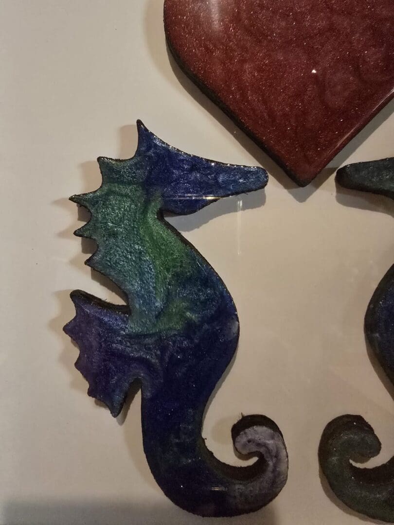 Handcrafted resin wall art of two seahorses beneath a red heart in a matt white box frame.