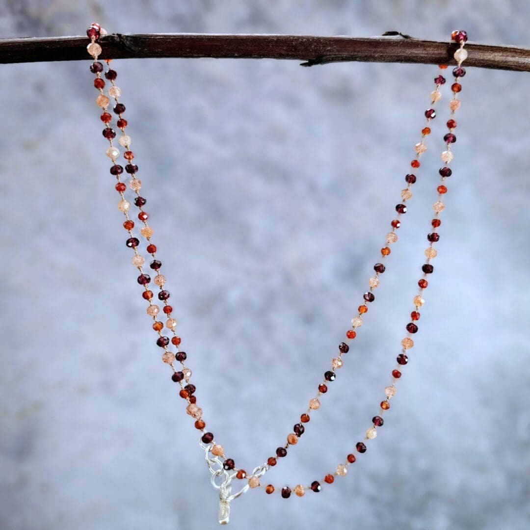 Garnet, sunstone and carnelian gemstone necklace, etched silver toggle, grey background hanging, Isobel Kelly Jewellery