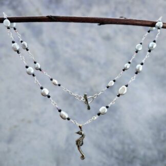 Silver seahorse necklace, baroque pearl, black spinel and tourmaline, hanging grey background, Isobel Kelly Jewellery