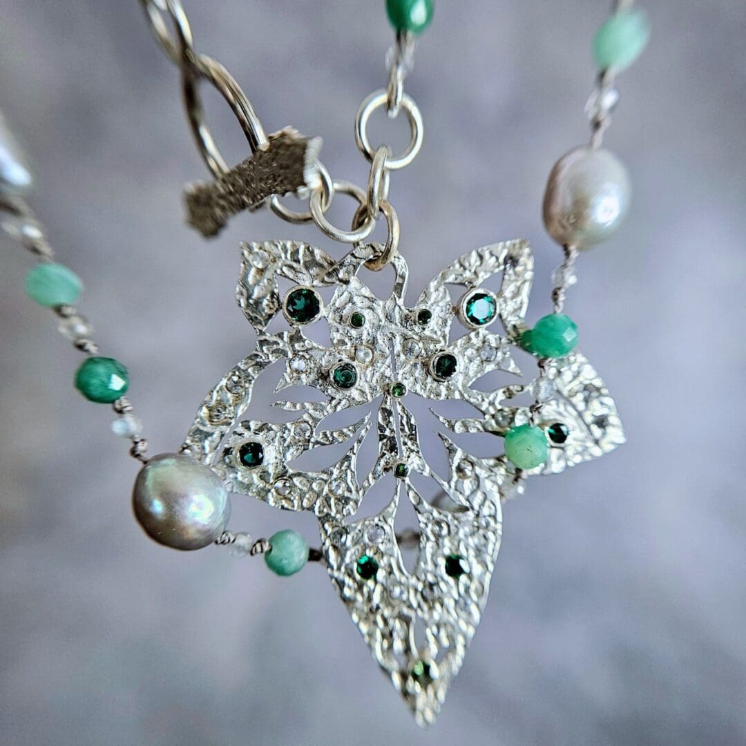 Etched sterling silver ivy pendant set with white sapphires, tsavorite garnets and lab emeralds, strung on a silk necklace with emerald, labradorite and baroque pearls. Pendant detail. Isobel Kelly Jewellery, Hants UK