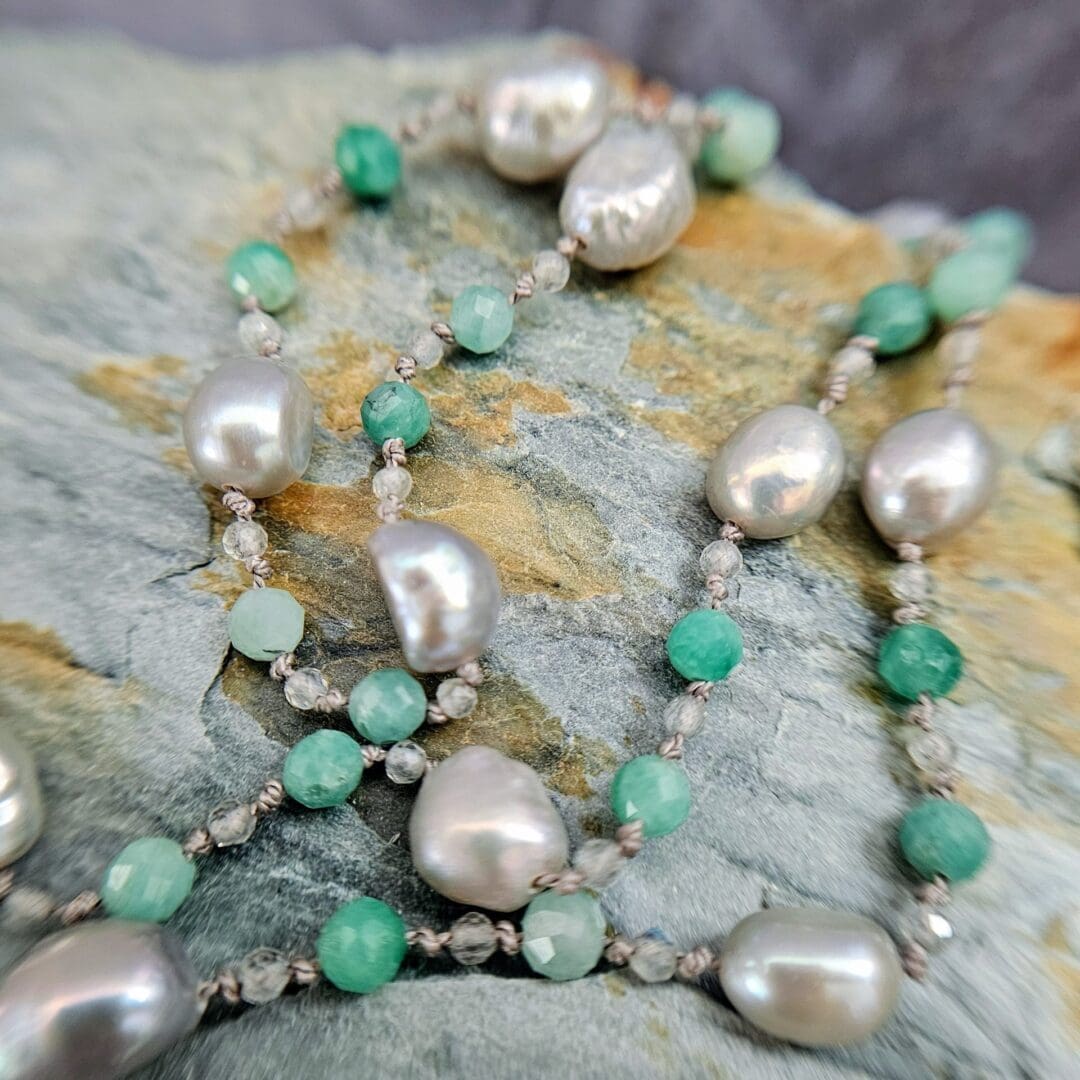 Etched sterling silver ivy pendant set with white sapphires, tsavorite garnets and lab emeralds, strung on a silk necklace with emerald, labradorite and baroque pearls. Bead close up. Isobel Kelly Jewellery, Hants UK