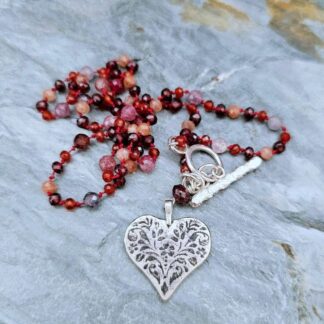 Garnet, sunstone and carnelian silver folk heart necklace, silver folk heart detail, heart detail grey background, Isobel Kelly Jewellery